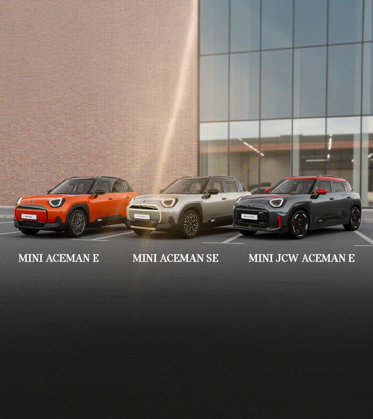 Gray MINI Aceman parked on a city street beside a bright purple and red building, featuring modern design and black roof.